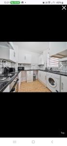 a large kitchen with white cabinets and a washer at The Wheatland House in London