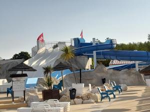 a water park with a water slide in the background at Mobil home camping les Charmettes 4 étoiles les MATHES en Charente Maritime prés du ZOO de la Palmyre 8 personnes tout confort 3 chambres 2salles de bains 2 WC Lave linge lave vaisselle Climatisation bien situé in Les Mathes
