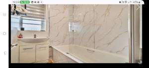 a white bathroom with a tub and a sink at The Wheatland House in London