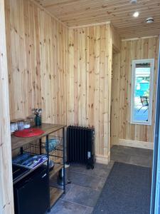 a room with a wooden wall with a stove and a table at Ardenbeg in Grantown on Spey