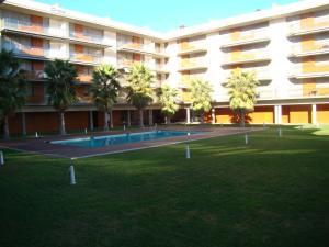 a large building with a swimming pool and palm trees at Apartamento Playa Esquirol in Cambrils