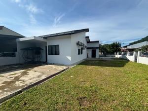 a white house with a grass yard in front of it at Rumah Bonda in Gua Sai