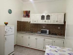 a kitchen with white cabinets and a white refrigerator at Hotel Maison Olga in Meknès