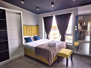 a bedroom with a bed and a large window at Mogosoaia High Living Penthouse in Chitila