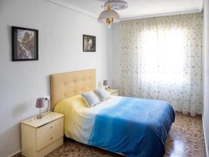 a bedroom with a bed with a blue blanket and a window at Apartamento La Mariola in Bocairent