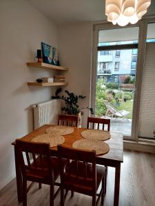 a dining room table with four chairs and a large window at Meta nad morzem in Pogórze