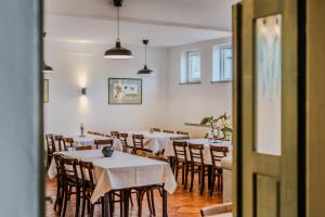a dining room with tables and chairs with white tablecloths at Rooms&Vinery Bregovi - Sobe in vinska klet Bregovi in Dobravlje
