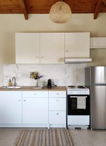 a kitchen with white cabinets and a sink and a stove at Ανέμη in Panayía +32 photos