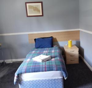 a bedroom with a bed with a plaid blanket and a night stand at Pokój 1osobowy in Moffat