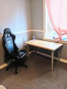 a black chair sitting next to a table and a window at Pokój 1osobowy in Moffat