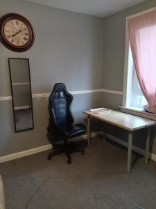 a office with a chair and a desk and a clock at Pokój 1osobowy in Moffat +1 photo