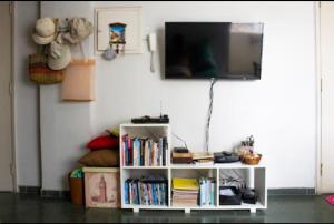 a white shelf with books and a tv on a wall at Vanderli - Deli in São Vicente