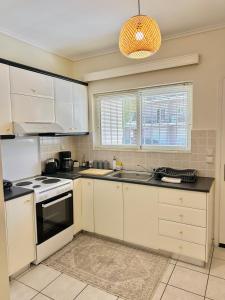 a kitchen with white cabinets and a stove top oven at Sophilia Garden escape in Patra