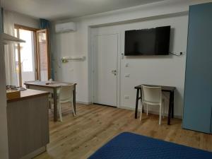 a living room with a table and a television on the wall at DH Studio Apartments in Castellammare del Golfo