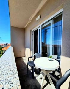 a balcony with a white table and chairs and a window at Bepo in Zadar
