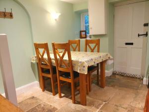 einen Esstisch mit 4 Stühlen, einem Tisch und einer Tür in der Unterkunft East View Cottage iow in Chalegreen