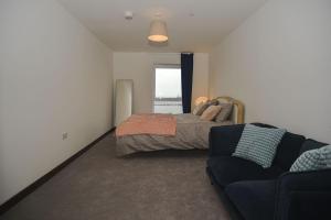 a bedroom with a bed and a couch and a window at Seaview City Lodge , 2- bedroom flat with Parking in Southend-on-Sea