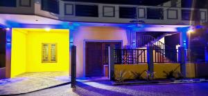 a house with a yellow wall and blue lights at Ananyah Villa in Trincomalee
