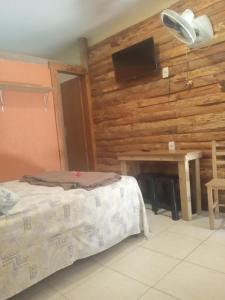 a bedroom with a bed and a table and a television at Morada do rosa ouvidor in Garopaba