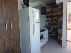a kitchen with a white refrigerator in a room at Suíte Praia leste 02 in Pontal do Paraná