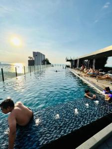 a man in a swimming pool next to the ocean at Best Location at Central Pattaya in Pattaya Central