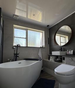 y baño con bañera, aseo y espejo. en Park Terrace Family Room, en Glastonbury