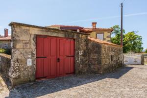 a red garage door on a stone wall at House Sopo in Vila Nova de Cerveira