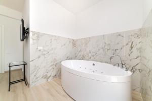 y baño con bañera blanca y paredes de mármol. en B&B Deluxe Room, en Salerno