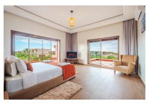 a bedroom with a bed and a chair and windows at Villa Dahlia Jacuzzi, Stove, Pool in Marrakesh