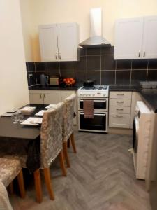 a kitchen with white cabinets and a table with chairs at Newly Decorated Spacious room, Women only in Bradford