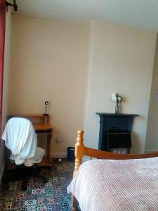 a bedroom with a bed and a desk and a fireplace at Newly Decorated Spacious room, Women only in Bradford