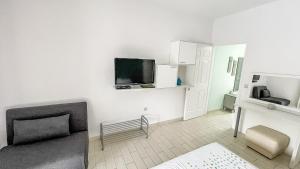 a white room with a couch and a tv on the wall at Seaside Apartments - Adults Only in Yénion