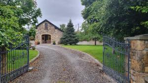 a driveway leading to a stone house with a gate at Katie's Lodge in Tawnaghmore