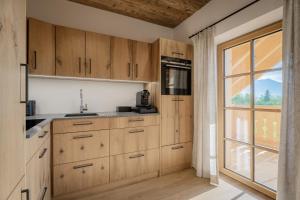 a kitchen with wooden cabinets and a large window at Arnestgut in Strobl