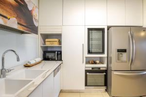a kitchen with white cabinets and a stainless steel refrigerator at GW002 Gugel Waves Amazing Seaview & Garden Family Apartments in Nahariyya