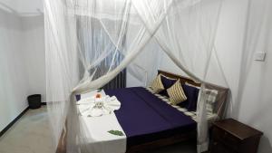 a bedroom with a canopy bed with purple sheets and pillows at Galhena Villa in Tangalle