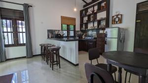 a kitchen with a refrigerator and a table and chairs at Galhena Villa in Tangalle