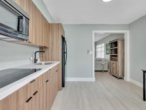 Una cocina con gabinetes de madera y un fregadero. en Modern Apt Near Beach – Views Wi-Fi, en Dania Beach