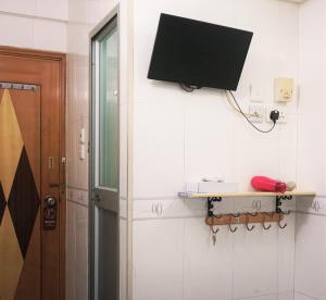 um quarto com uma porta e uma televisão na parede em Beverly Guest House em Hong Kong