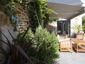 a patio with an umbrella and chairs and plants at Maison de caractère à Corseul, jardin et piscine in Corseul