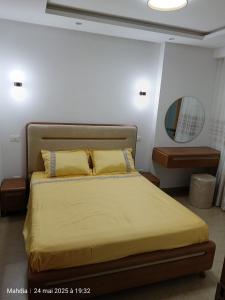 a bedroom with a bed with yellow sheets and a mirror at Ariane Appartment - Residence Espadon in Mahdia