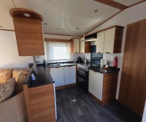 a small kitchen with white cabinets and a couch at Woodside, Meadows Retreat, Cockermouth in Plumbland