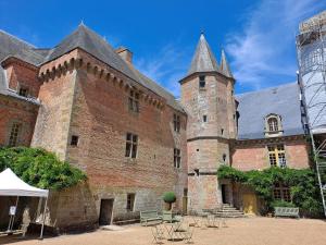 ein großes Backsteingebäude mit einem Turm mit einem Dach in der Unterkunft Pause zen dans le Perche Nature & calme 