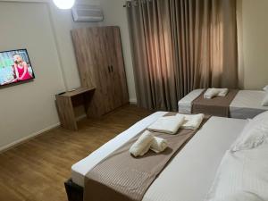 a hotel room with two beds and a tv at Eriks Rooms in Tirana