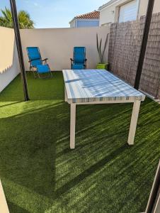 a picnic table on a lawn with two chairs at Pornic Studio in Pornic