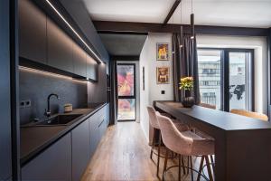 a kitchen with black cabinets and a counter with stools at Central Paul Deluxe Apartment - by Open House in Timişoara