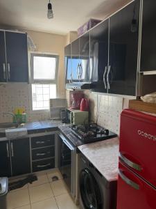 a kitchen with black cabinets and a red refrigerator at Appartement FNIDEQ BAB CEUTA in Fnidek