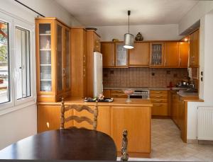 a kitchen with wooden cabinets and a table in it at St Nickolas Guest House in Artemida