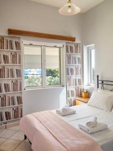 a bedroom with a bed and a window and books at St Nickolas Guest House in Artemida