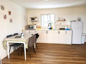 a kitchen with a table and a white refrigerator at בקתה 512- אירוח בדרום הגולן in Giv'at Yo'av +34 photos
